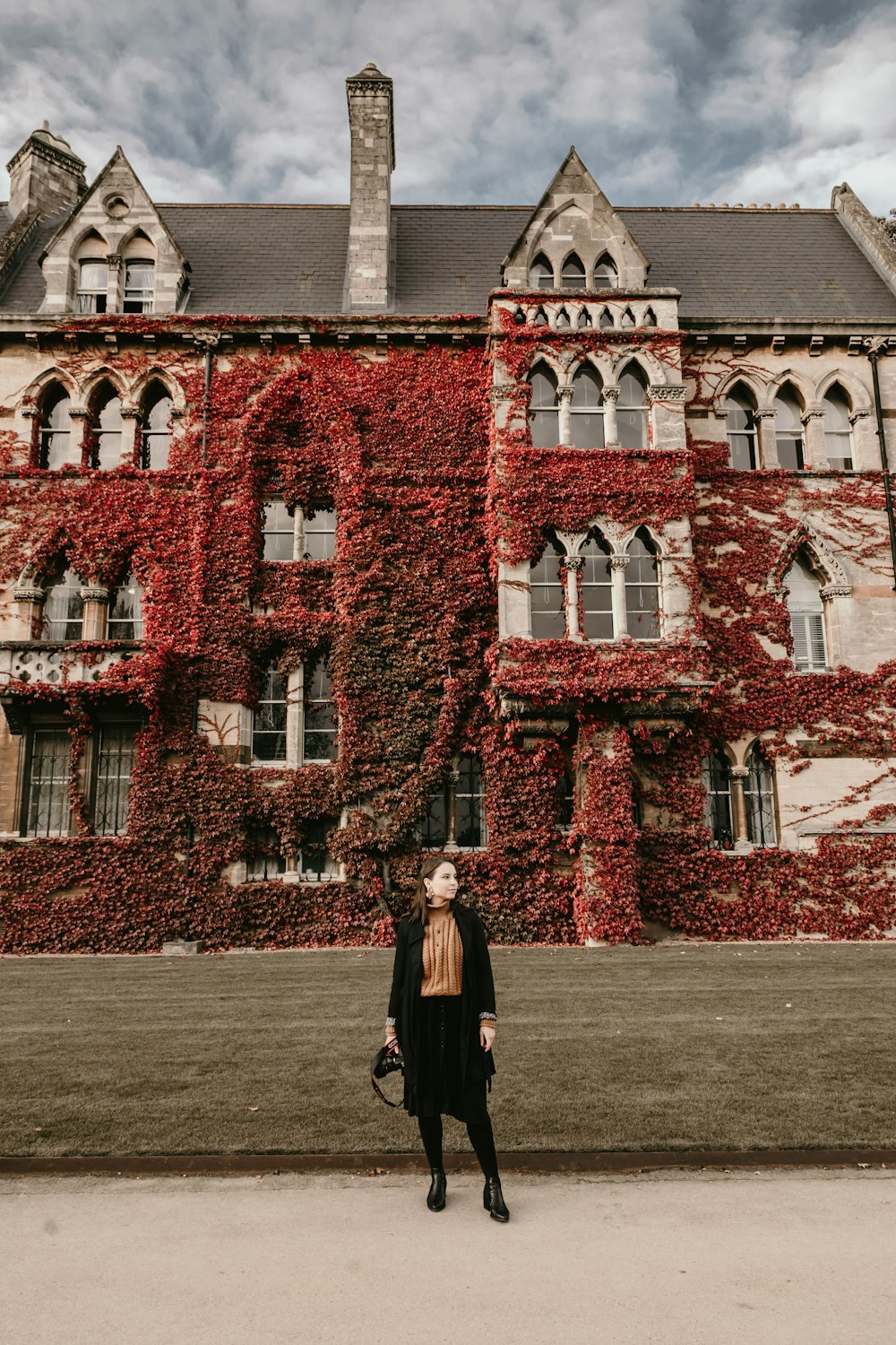 woman in black coat standing in front of brown brick building