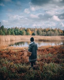 man in black jacket and black pants standing on brown grass field during daytime