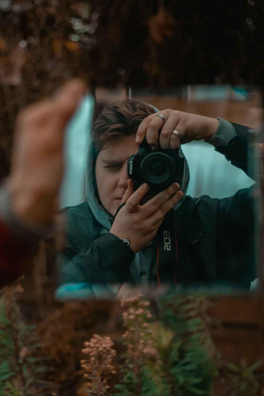 Frau in schwarzer Jacke fotografiert mit schwarzer DSLR-Kamera