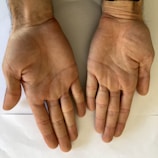 Two open hands with fingers slightly apart resting on a flat surface, with visible lines and creases on the palms.