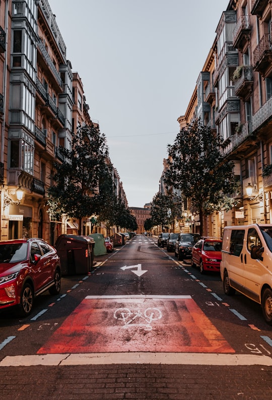 cars parked on the side of the road in between buildings during daytime in San Sebastián Spain