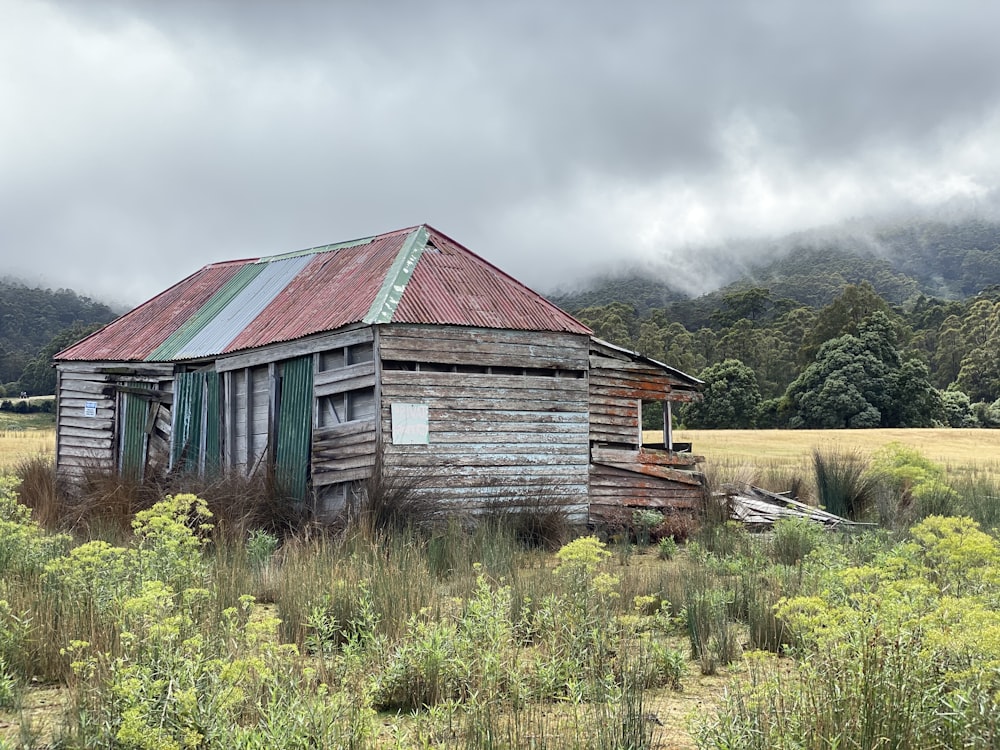 brown wooden house on green grass field under cloudy sky during daytime