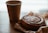 Close-up of a hand holding a cinnamon spice cookie over a rustic wooden table with a warm café background.