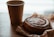 Close-up of a hand holding a cinnamon spice cookie over a rustic wooden table with a warm café background.