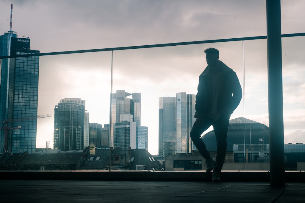 man in black jacket and black pants standing on black metal bar during daytime