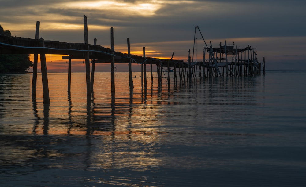 silhouette of wooden dock on sea during sunset