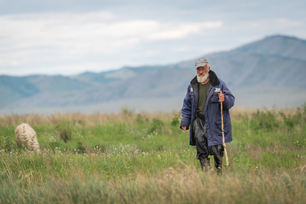 uomo in giacca nera in piedi sul campo di erba verde durante il giorno