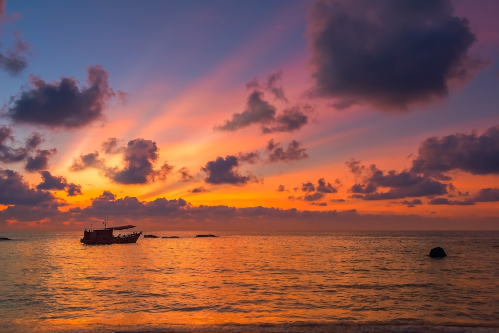 silhouette of boat on sea during sunset