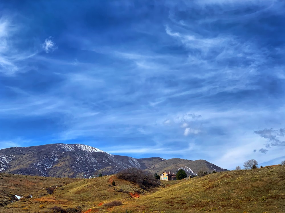 green grass field near mountain under blue sky during daytime