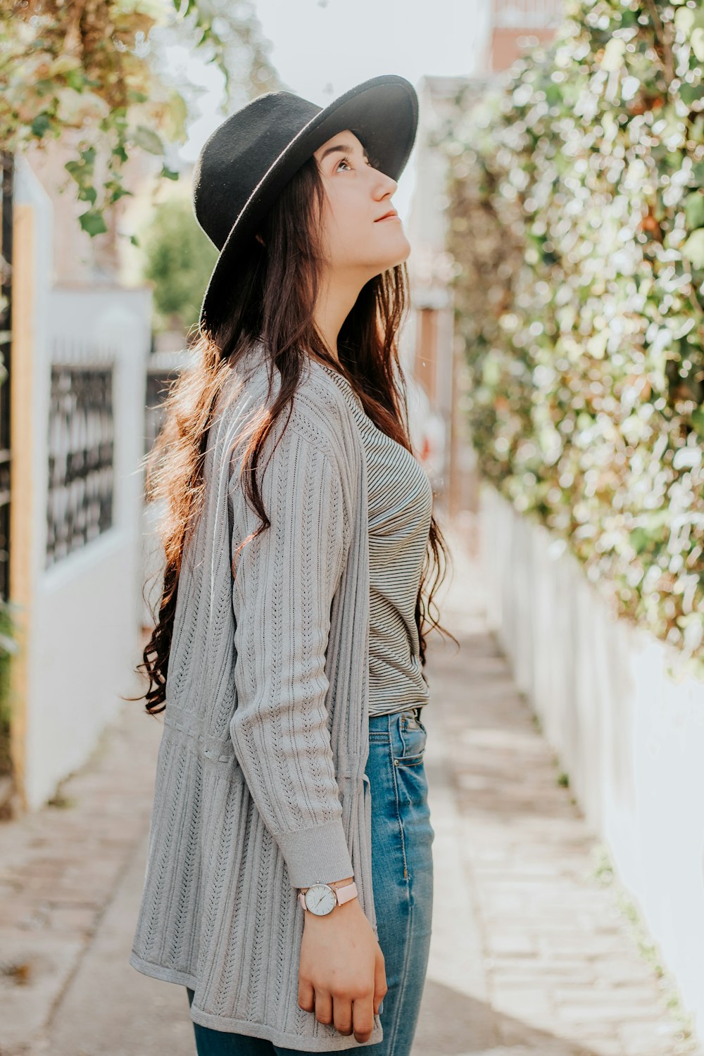 woman in white and black striped long sleeve shirt and blue denim jeans standing on sidewalk