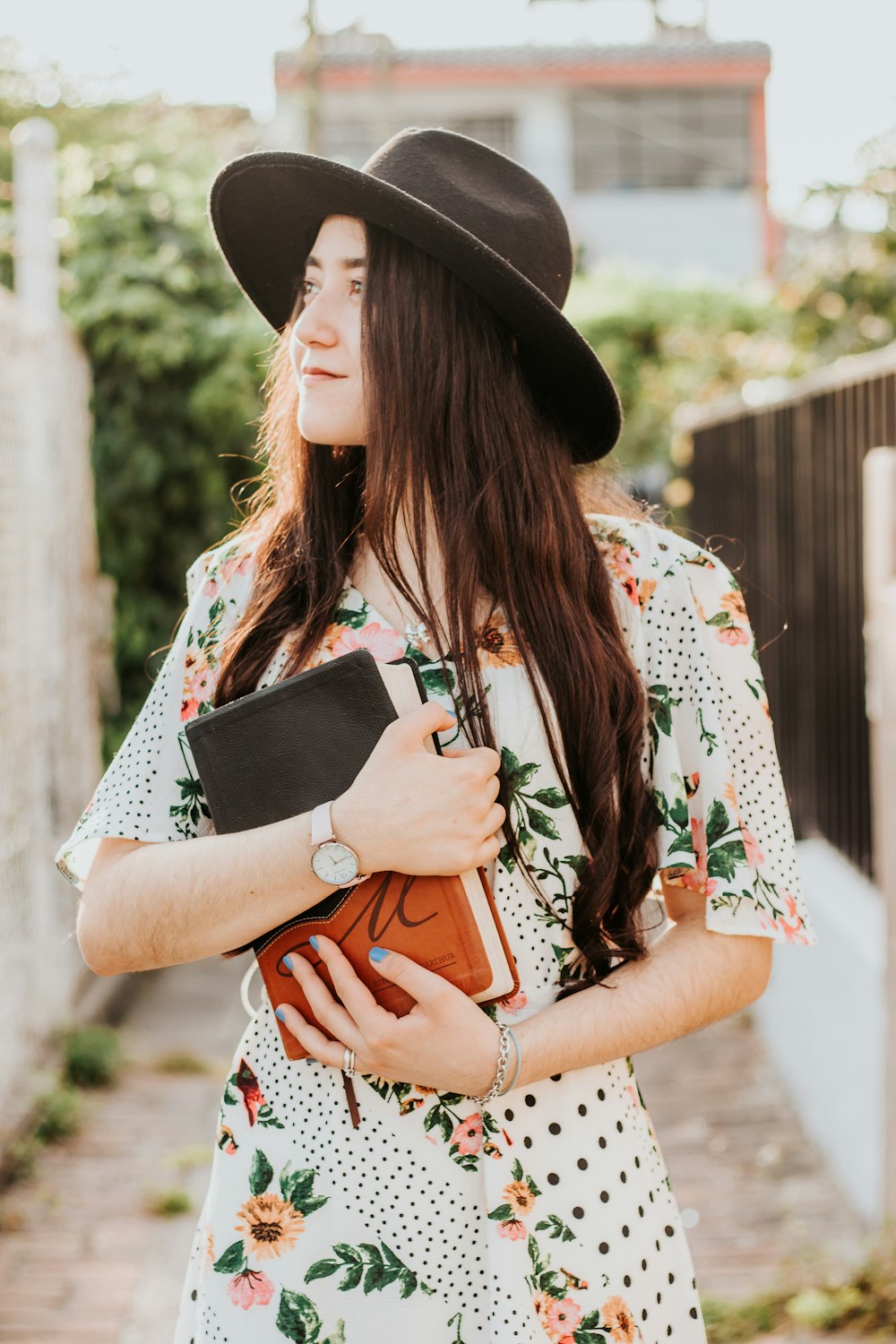 woman in white green and red floral dress wearing black fedora hat