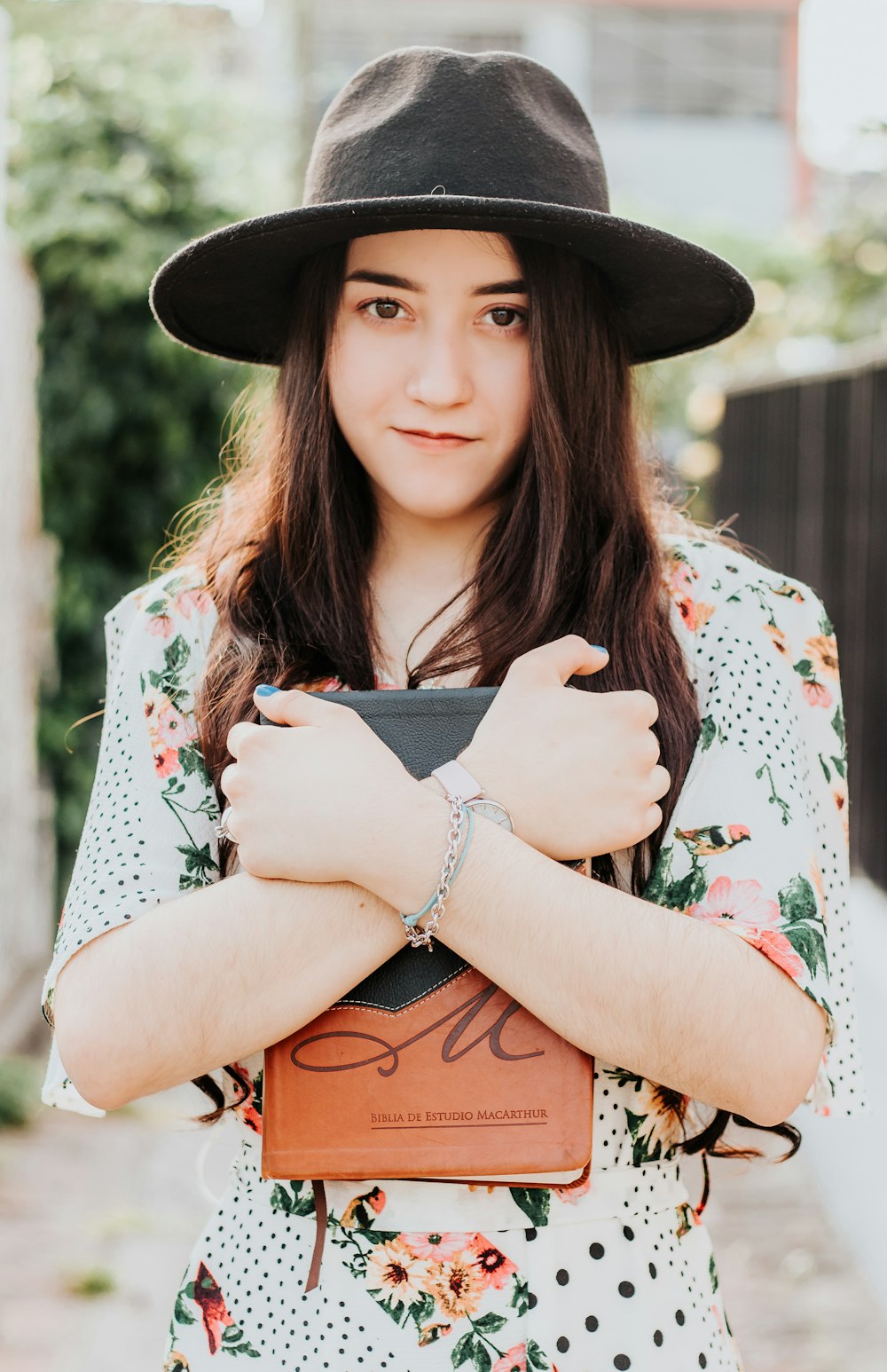 woman in white green and red floral dress wearing black fedora hat