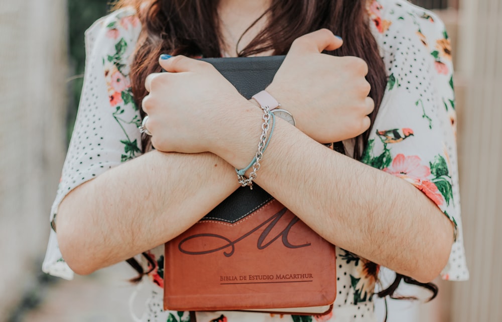 woman in silver bracelet holding brown book