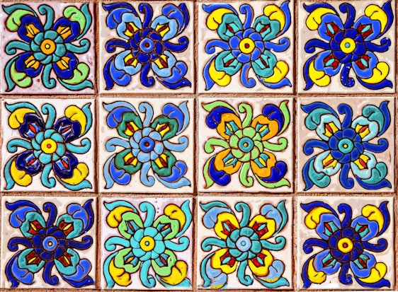 A collection of colorful decorative tiles featuring intricate floral patterns. Each tile displays a symmetrical design with vivid hues of blue, green, yellow, and red, arranged in a repetitive grid.