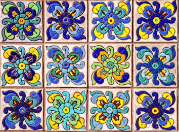 A collection of colorful decorative tiles featuring intricate floral patterns. Each tile displays a symmetrical design with vivid hues of blue, green, yellow, and red, arranged in a repetitive grid.