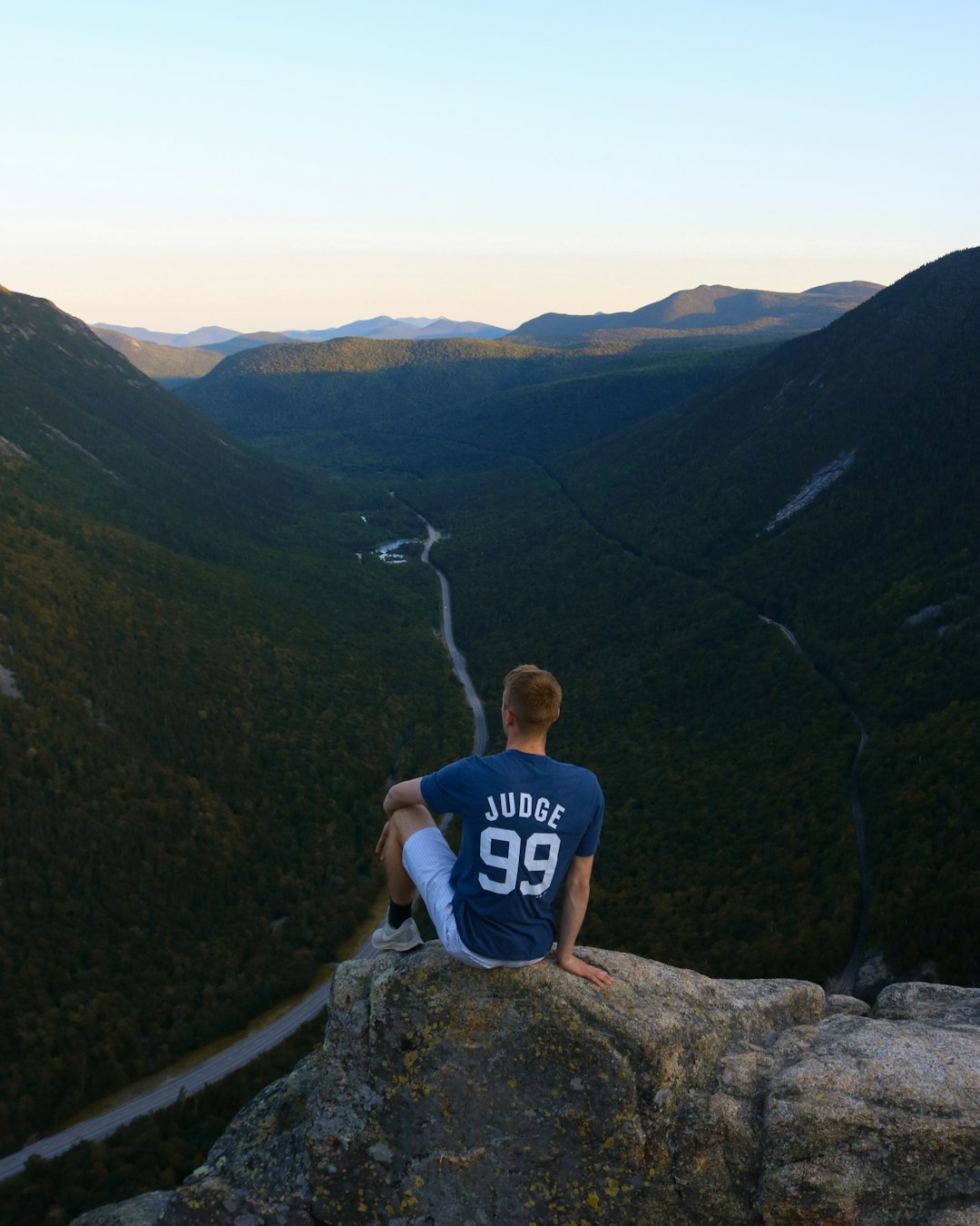 man in blue and white crew neck t-shirt sitting on rock