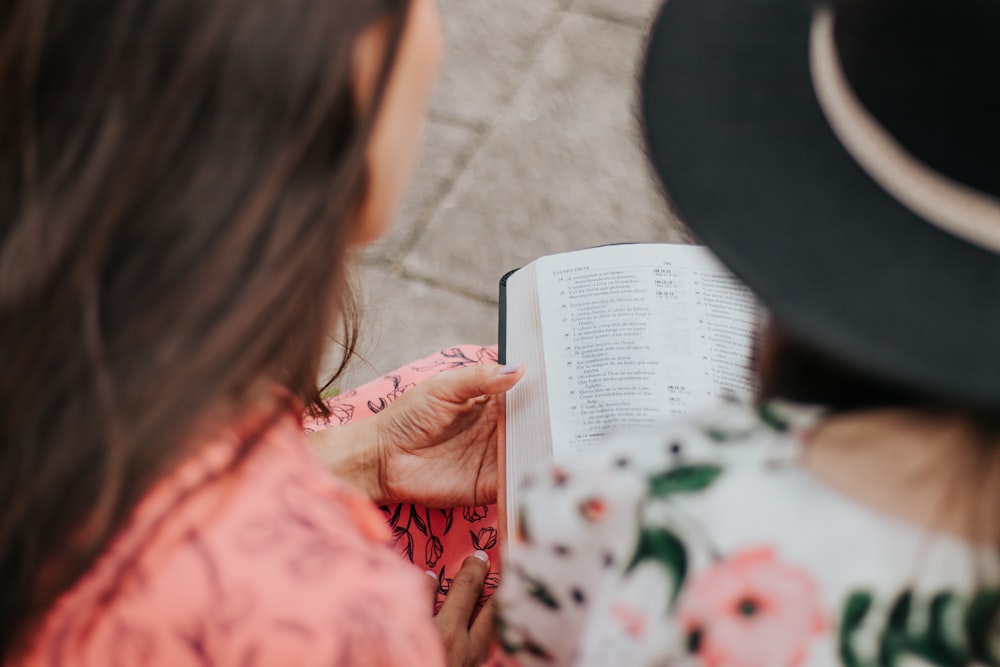 girl in pink and white floral long sleeve shirt reading book