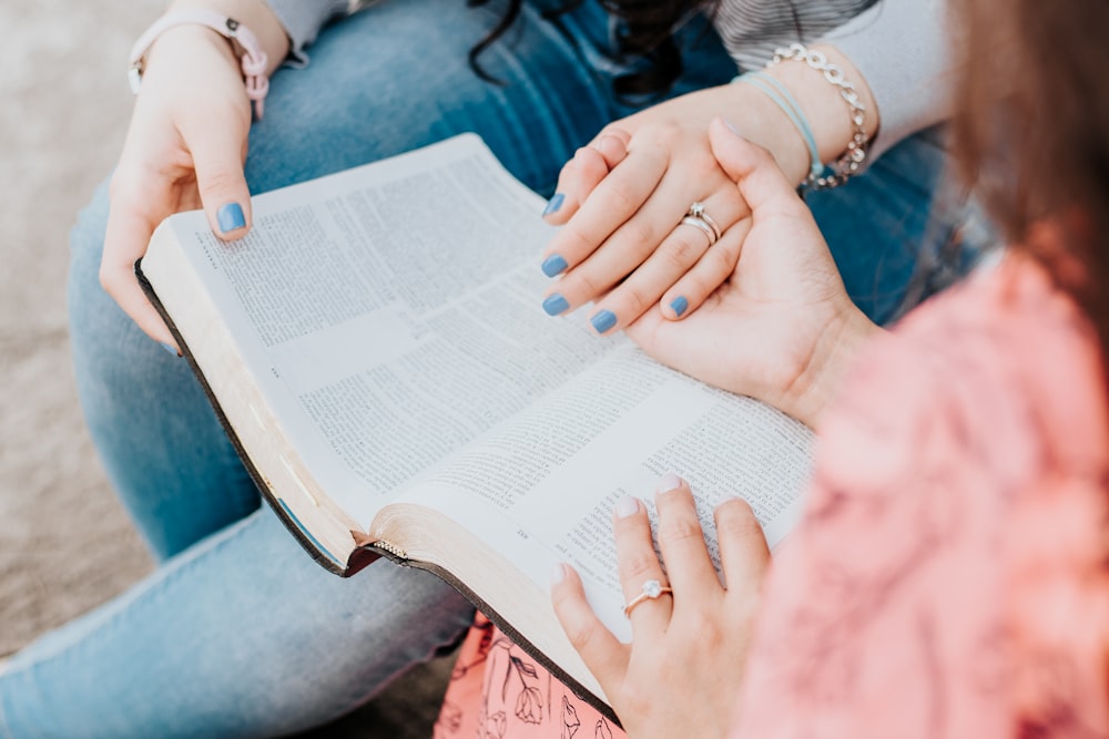 person in silver ring and white beaded bracelet reading book