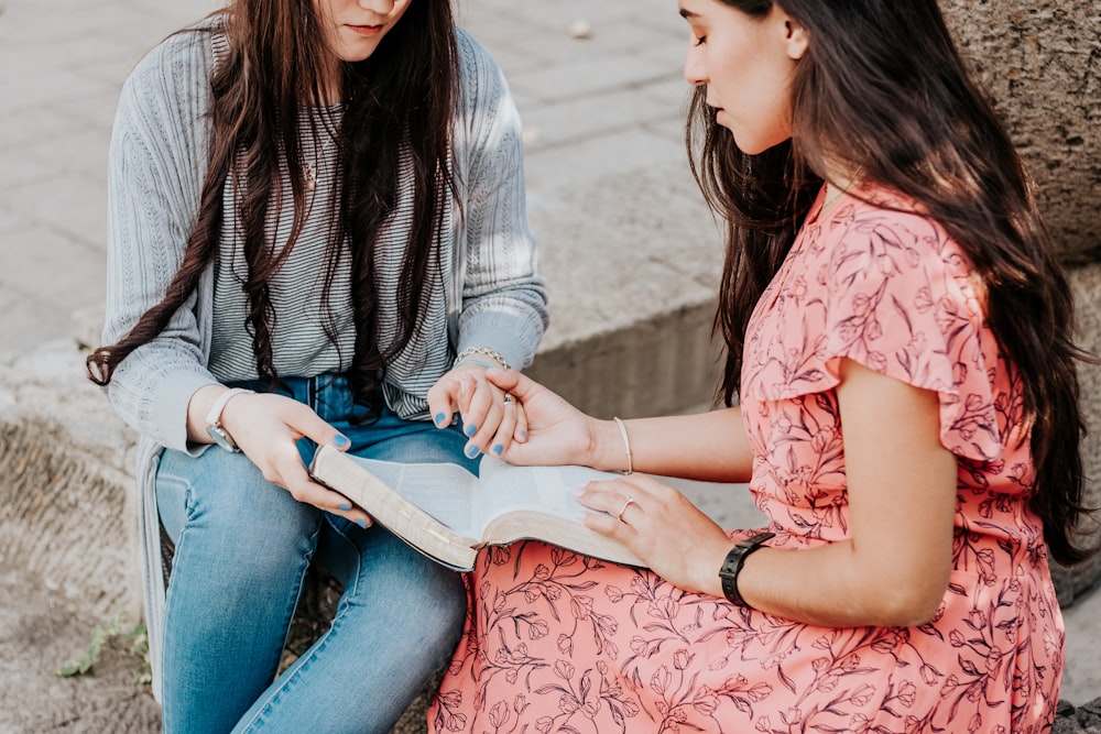 woman in white and black striped long sleeve shirt and blue denim jeans sitting on concrete