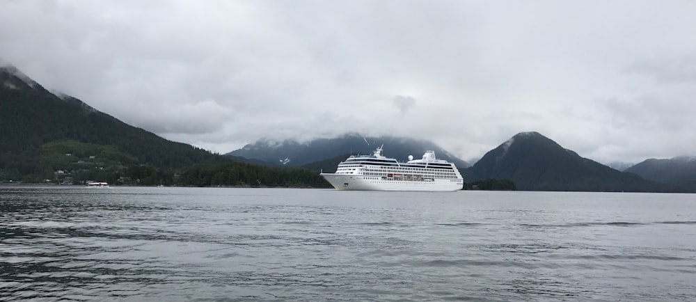 white cruise ship on sea under white clouds