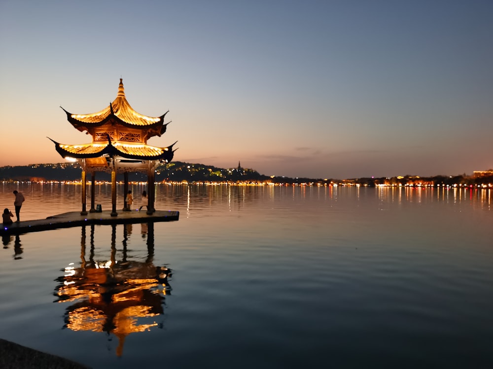 brown wooden gazebo on body of water during sunset