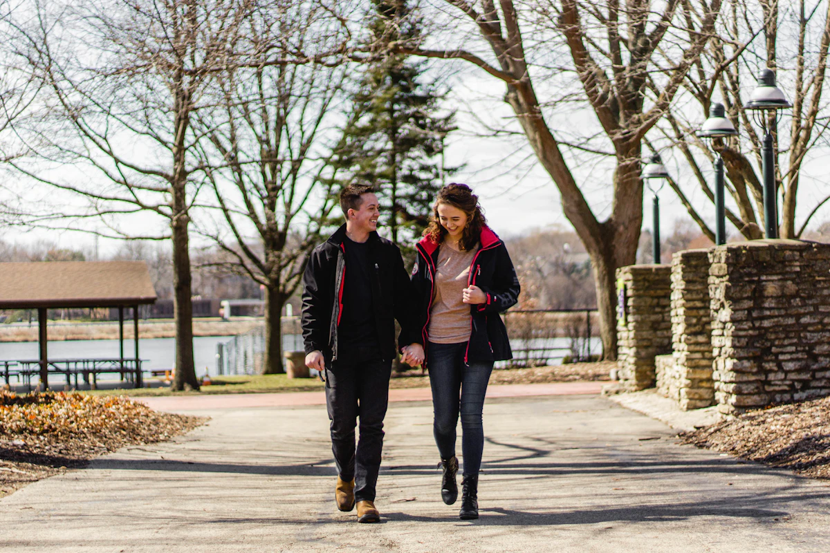 A couple walking together along a tree-lined park path