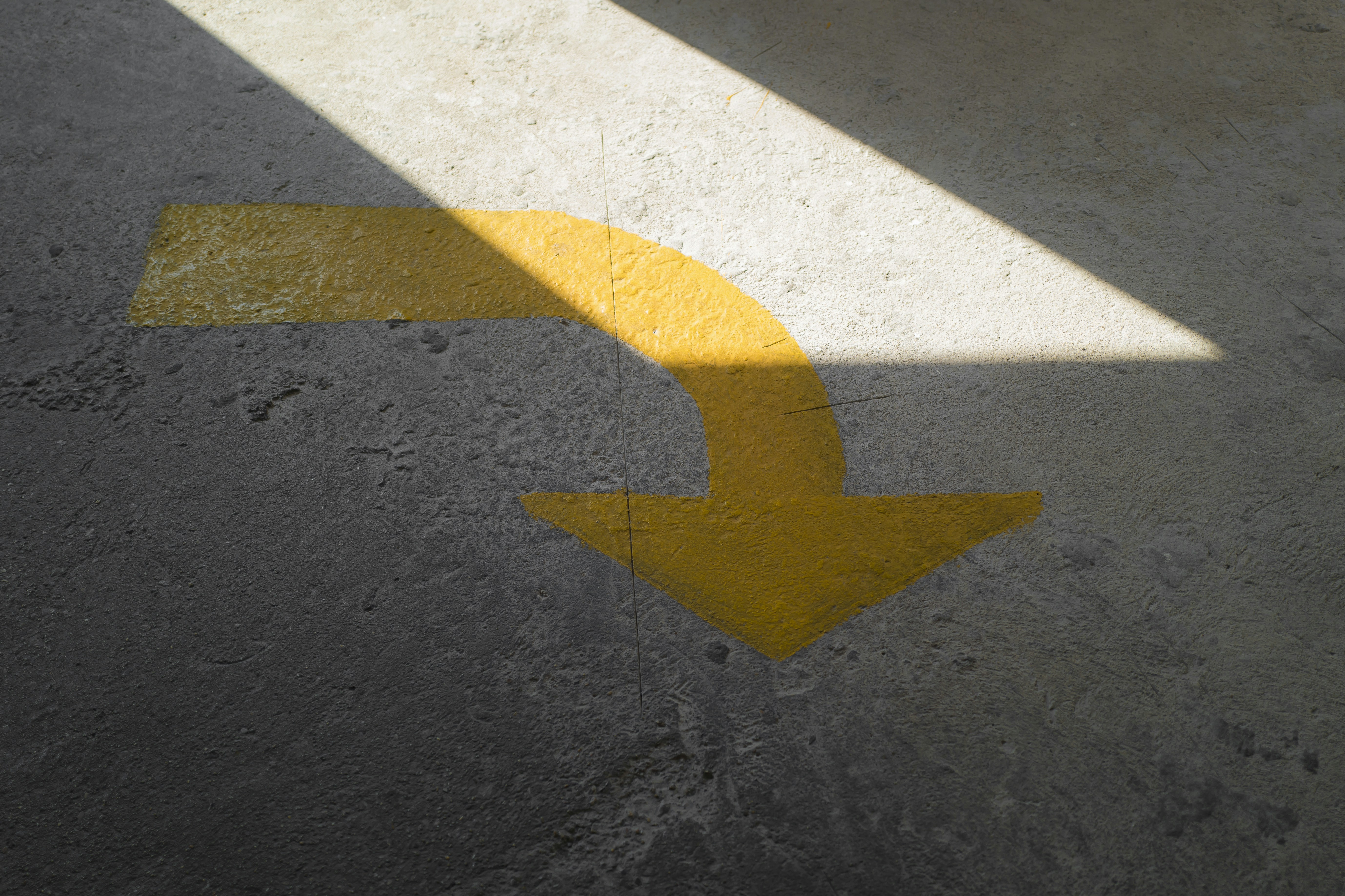 yellow arrow sign on gray asphalt road