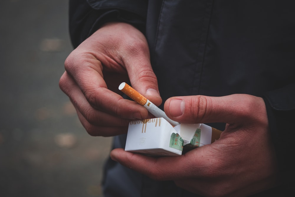 person holding white and brown cigarette stick
