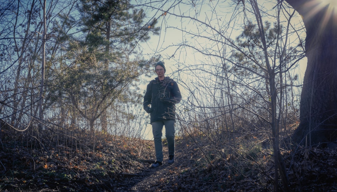 man in black jacket standing on brown dried leaves during daytime