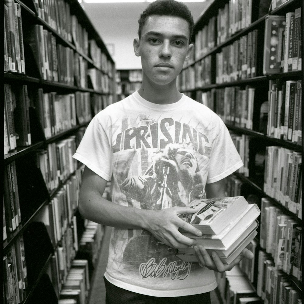 hombre en camiseta blanca de cuello redondo sosteniendo un libro