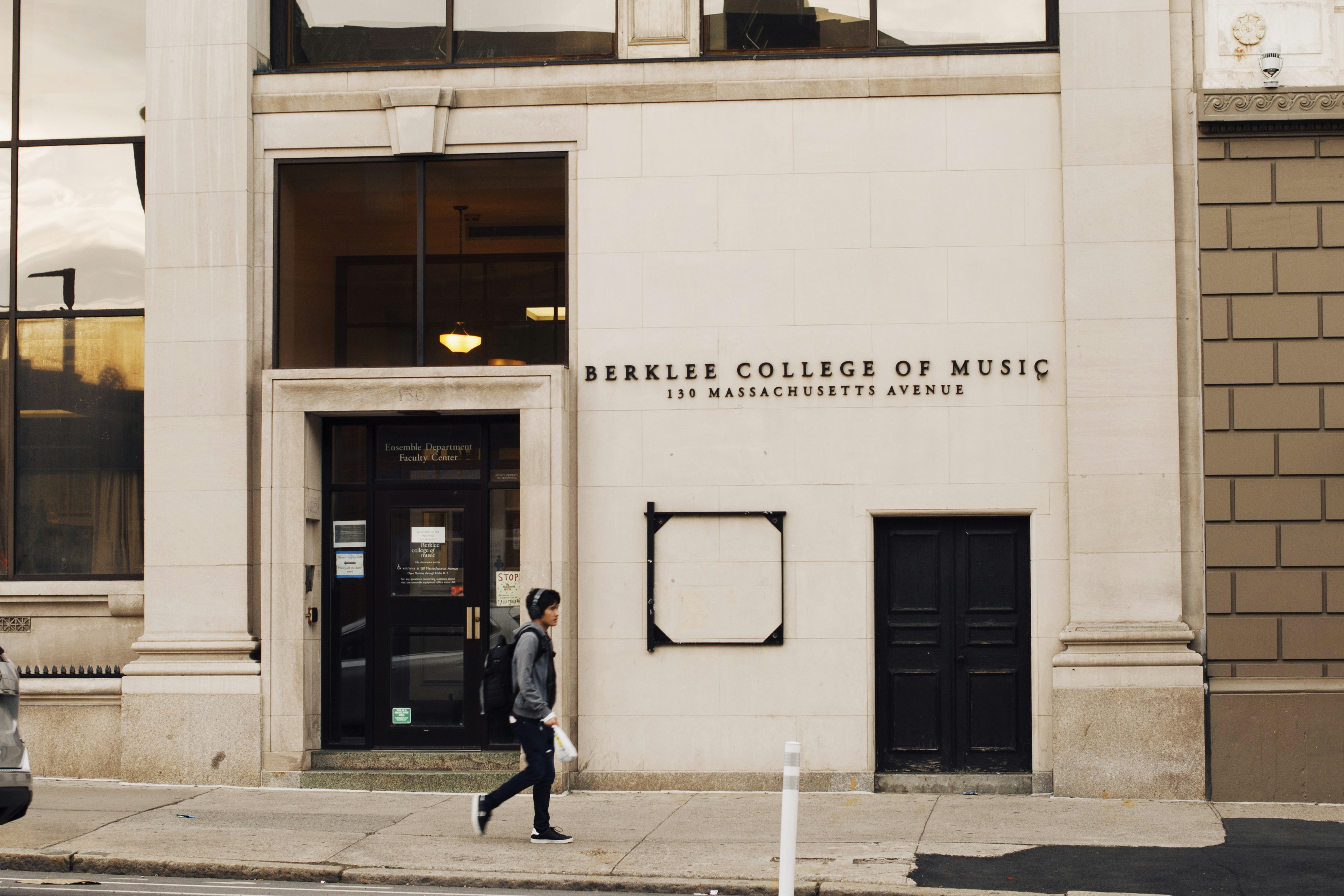 man in black jacket walking on sidewalk near building during daytime