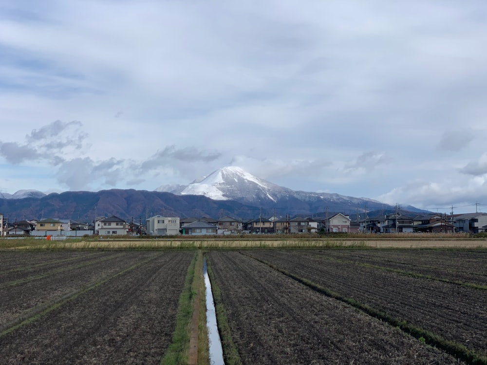 green grass field near mountain under white clouds during daytime