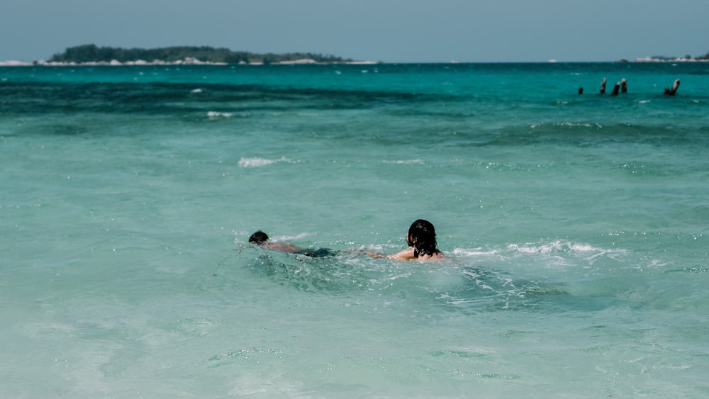 woman in black bikini swimming in the sea during daytime