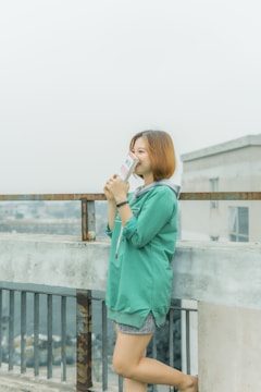 A person smiling while reading an ebook on a sunny balcony.