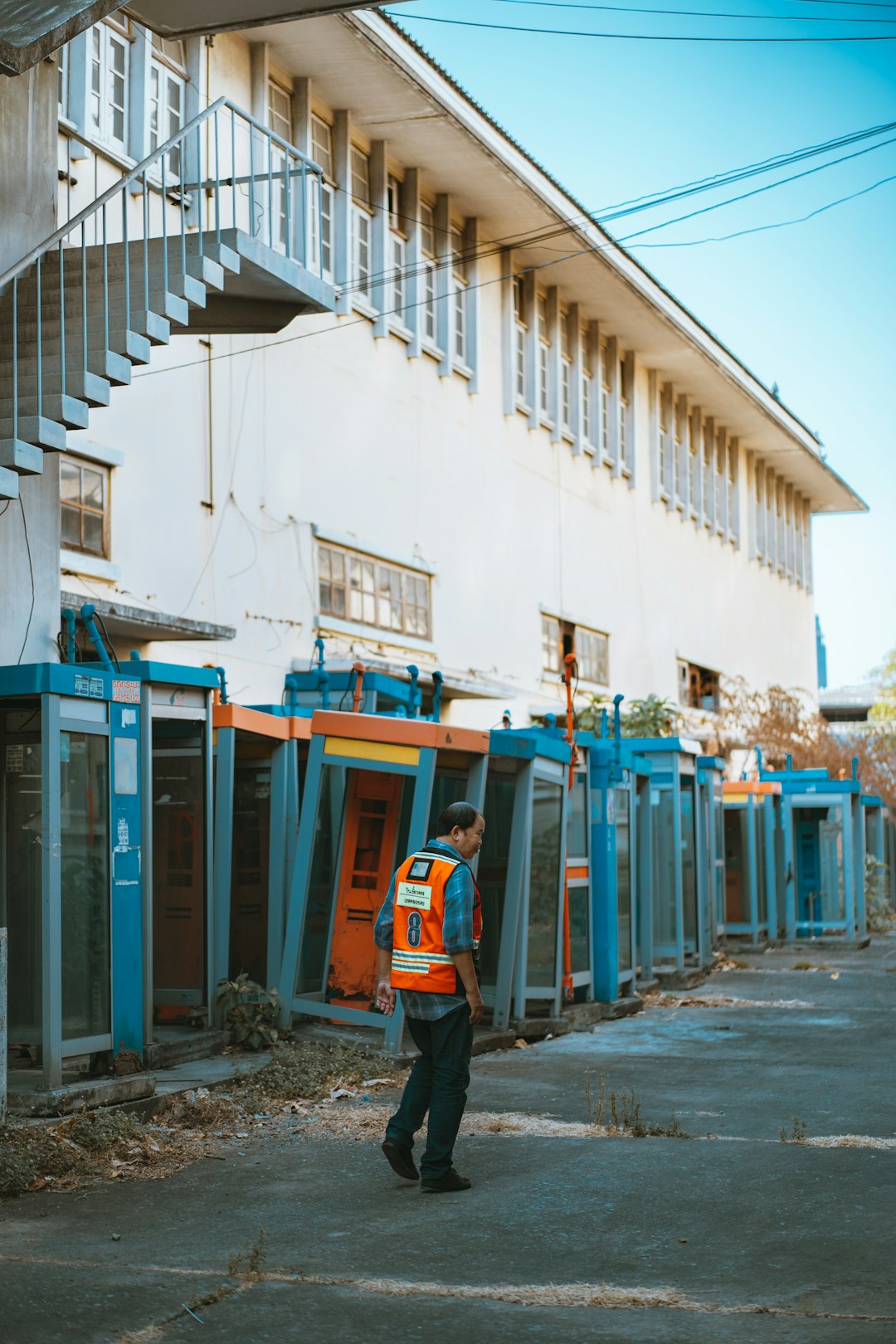 man in orange jacket standing near blue and white building during daytime