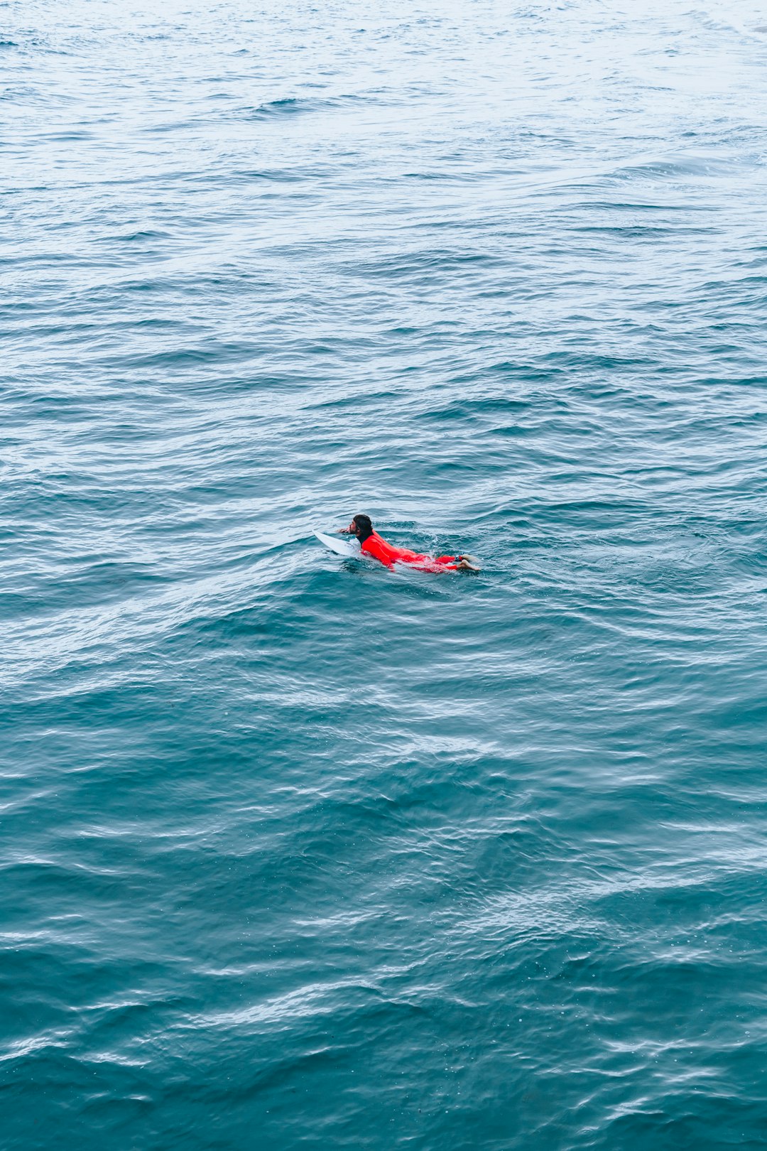 person in red wetsuit surfing on blue sea water during daytime
