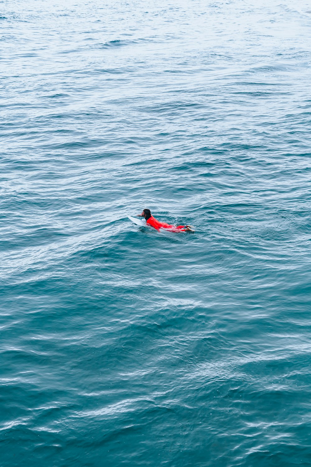 person in red wetsuit surfing on blue sea water during daytime