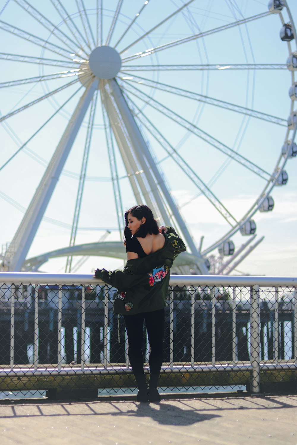 woman in black jacket and black pants standing on bridge
