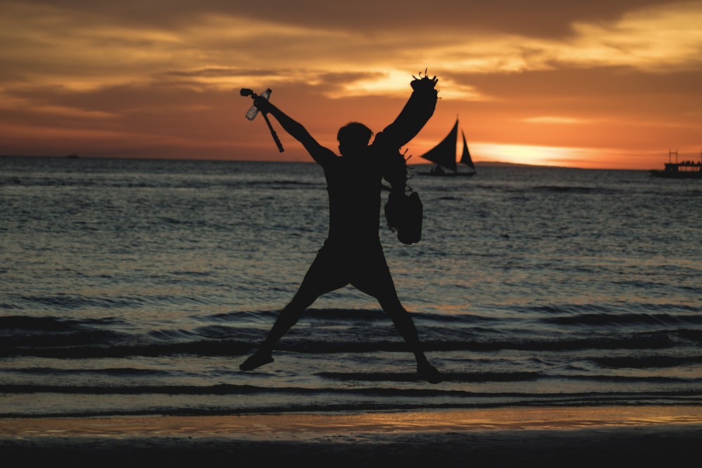 silhouette of woman jumping on beach during sunset