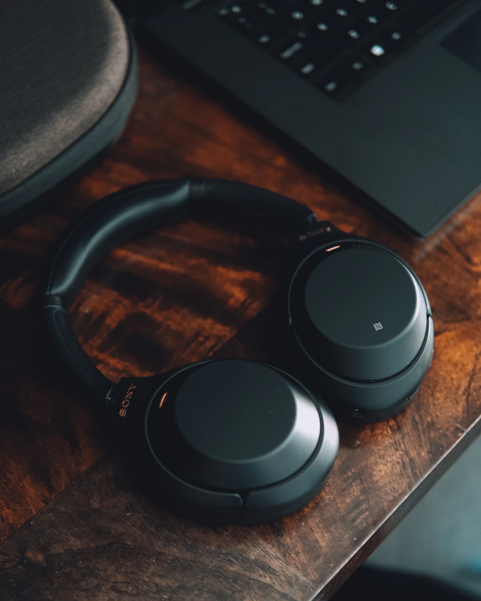 Over-ear headphones arranged on a wooden desk beside a computer