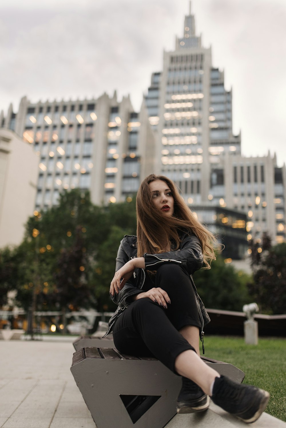 woman in black long sleeve shirt and black pants sitting on gray concrete bench during daytime