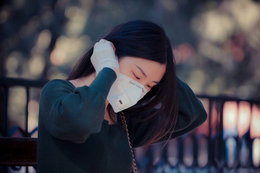 woman in black sweater covering her face with her hands