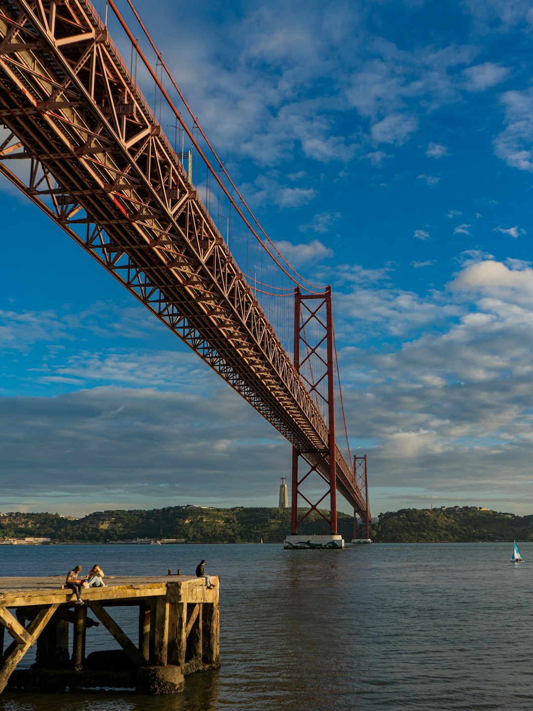 people sitting on brown wooden dock under blue sky during daytime