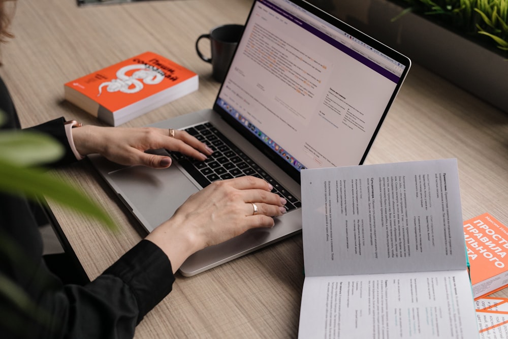 person using macbook pro on brown wooden table