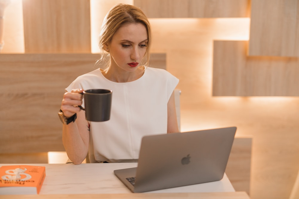 woman in white crew neck t-shirt holding black ceramic mug