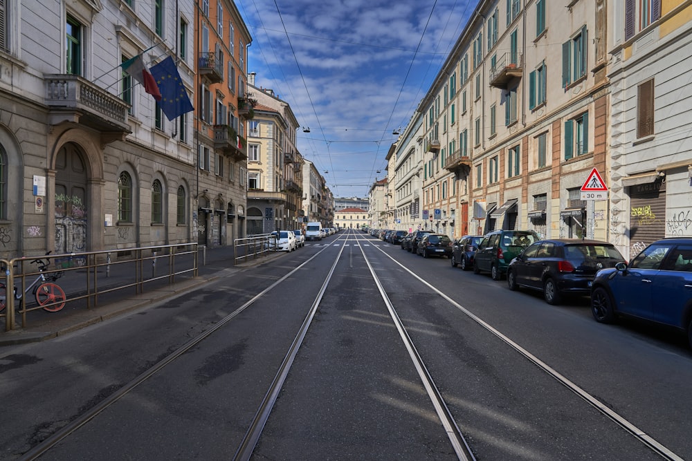 cars parked on side of the road in between buildings during daytime