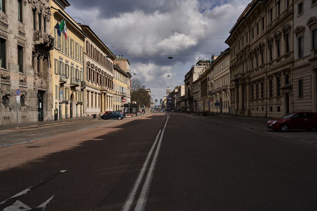 empty road between buildings under cloudy sky during daytime