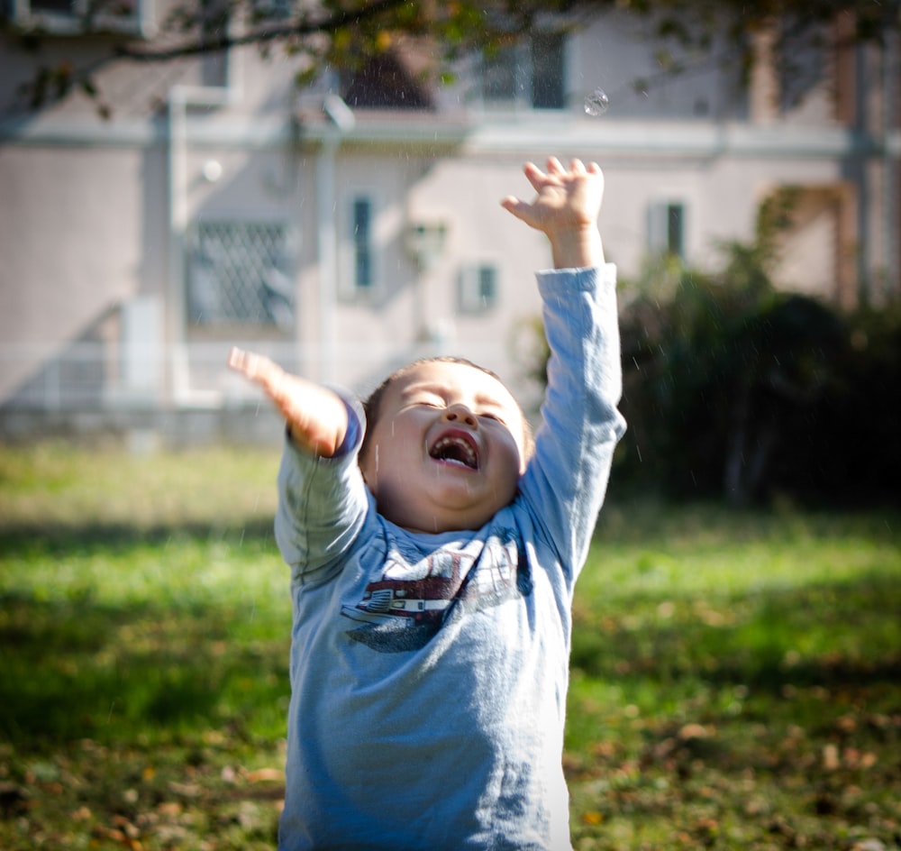 girl in blue long sleeve shirt raising her hands