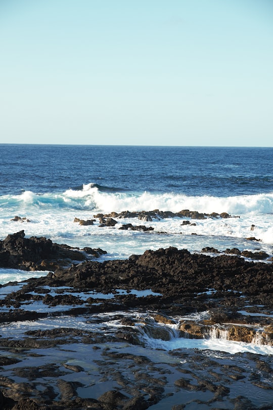 brown rocky shore with ocean waves crashing on shore during daytime in São Miguel Portugal