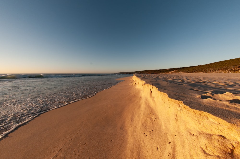 brown sand near body of water during daytime